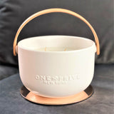 Indulge in the Bergamot and Clove Perfumed Estate Candle from One Preevay. Handcrafted with premium essential oils and soy wax, it features a stunning porcelain bowl with a silver-plated lid and leather strap. Elevate your ambiance all year around 